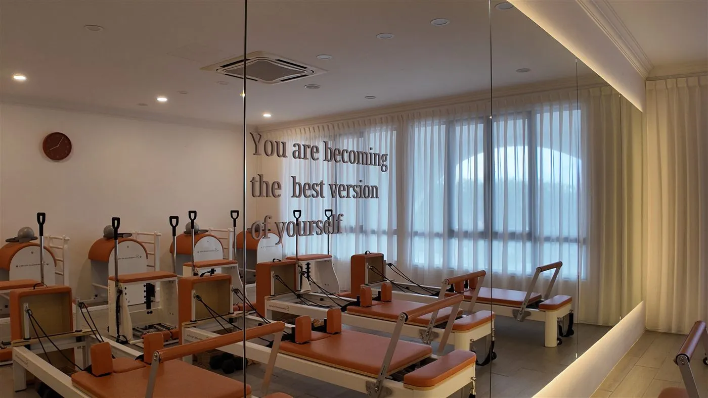 Warm sunlight across the Pilates reformers at SuperShape Wellness